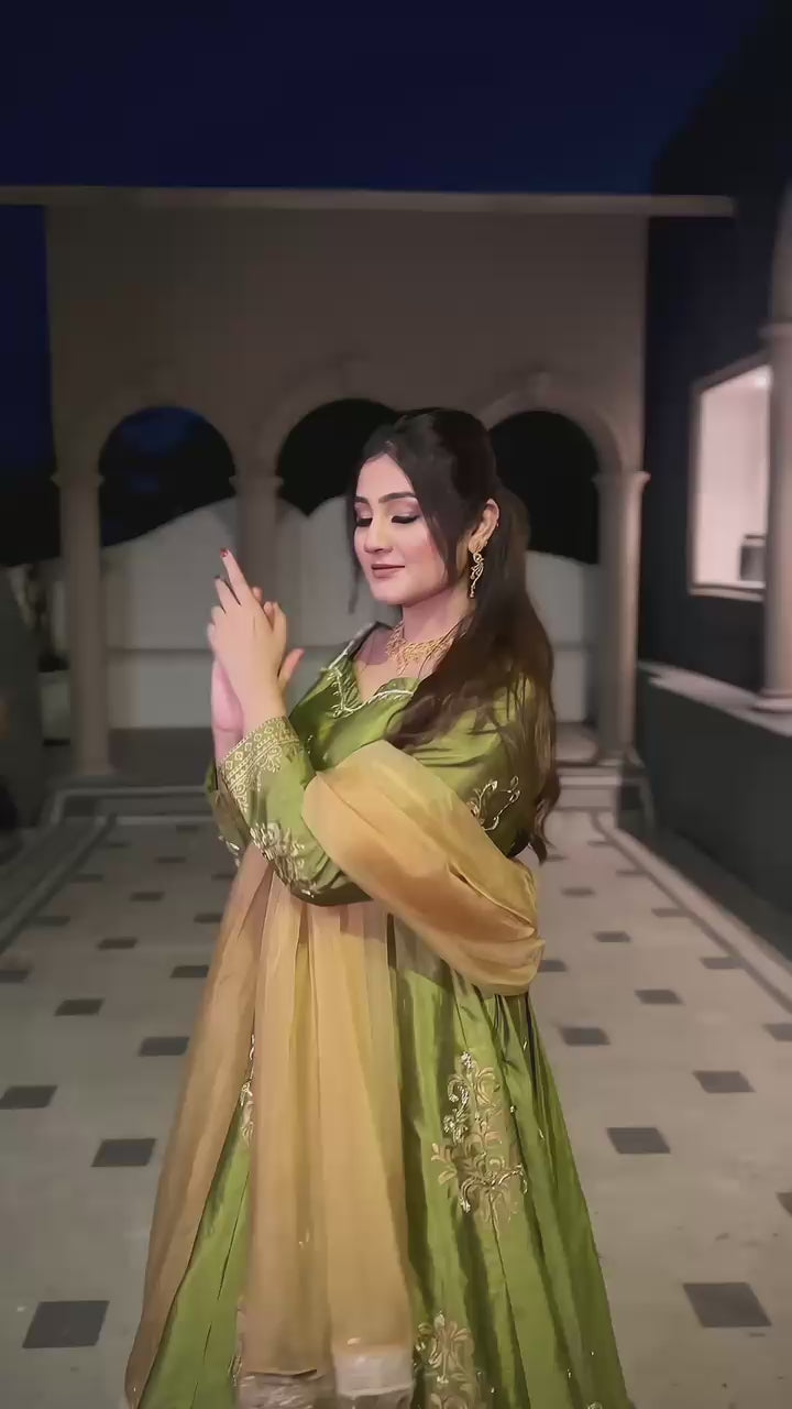 Load video: Witness the enchanting swirl of a Nawabi princess in this traditional Pishwas. Intricate golden embroidery dances on lush emerald green silk , a true masterpiece from Nawabzadi